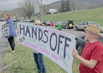 People holding large HANDS OFF banner